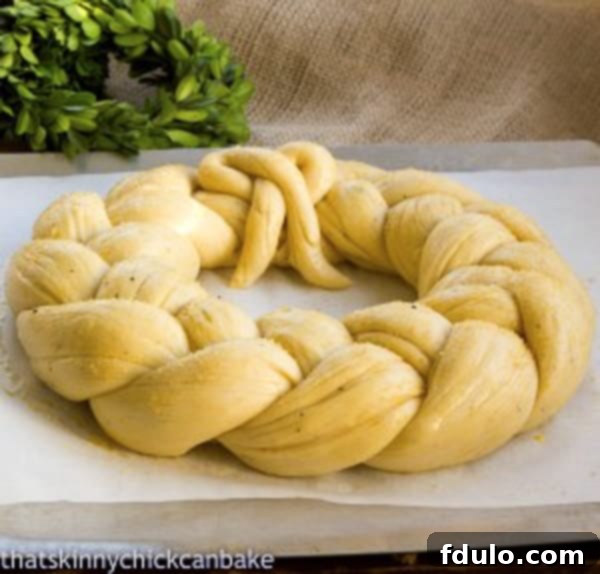 Finnish Pulla Bread - a festive yeast bread recipe shaped into a wreath for Christmas A festive holiday yeast bread recipe, shaped into a beautiful wreath and adorned with almonds and pearl sugar, ready for the oven on a baking sheet.