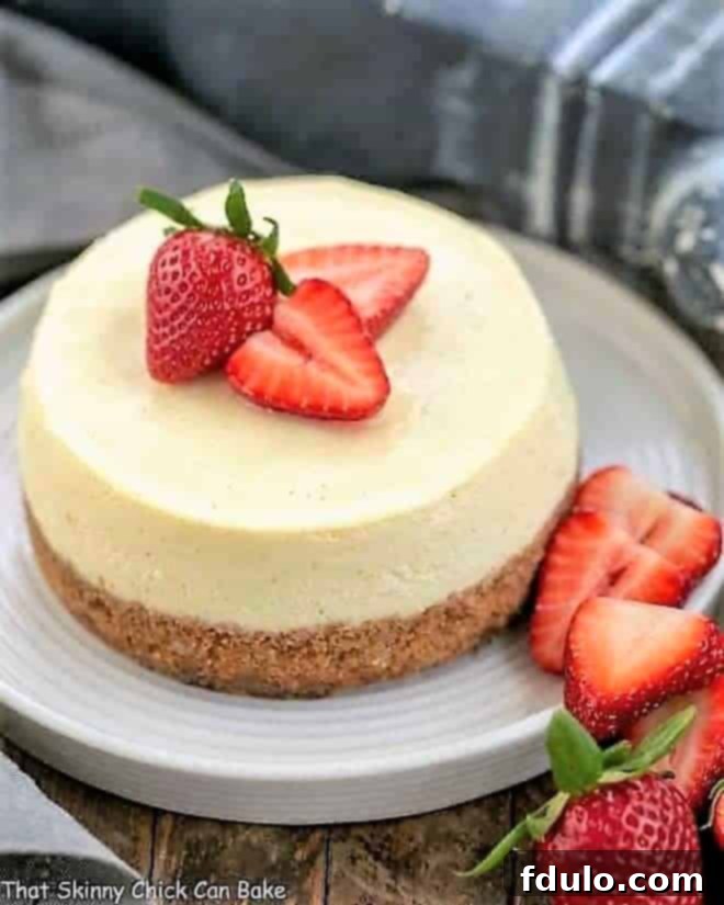 Beautifully garnished Vanilla Bean Instant Pot Cheesecake on a white serving plate, adorned with fresh strawberries, ready to be enjoyed.