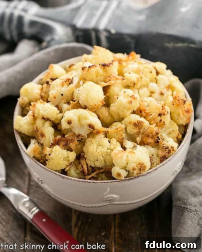 A vibrant white serving bowl filled with perfectly oven-roasted cauliflower florets, showcasing their golden-brown edges and inviting texture, ready to be served as a delicious side dish.
