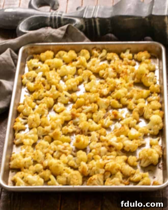 Close-up of roasted cauliflower on a baking sheet, showing perfectly tender florets with golden-brown, caramelized edges.