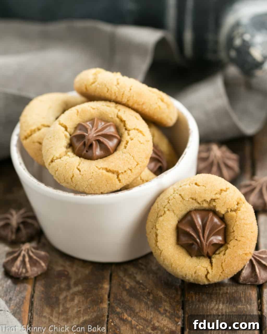 A small white bowl filled with Star of Bethlehem Cookies, with one cookie playfully leaning against the bowl, highlighting its perfect shape and chocolate star topping.