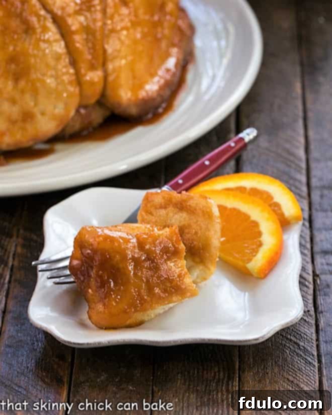 Discover the magic of Easy Monkey Bread, a delightful breakfast or brunch indulgence made simple with smart shortcuts that don't compromise on flavor or deliciousness! Close-up of golden brown, pull-apart Easy Monkey Bread pieces on a small white plate, garnished with fresh orange slices, highlighting its soft texture and caramelized glaze.