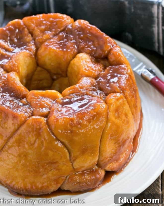 This Easy Bubble Bread is a delicious, crowd-pleasing breakfast or brunch treat that consistently earns rave reviews for its simplicity and irresistible flavor! A whole Easy Monkey Bread loaf on a beautiful white serving plate, showing the full-sized golden brown roll dough pieces, ready to be pulled apart and enjoyed.