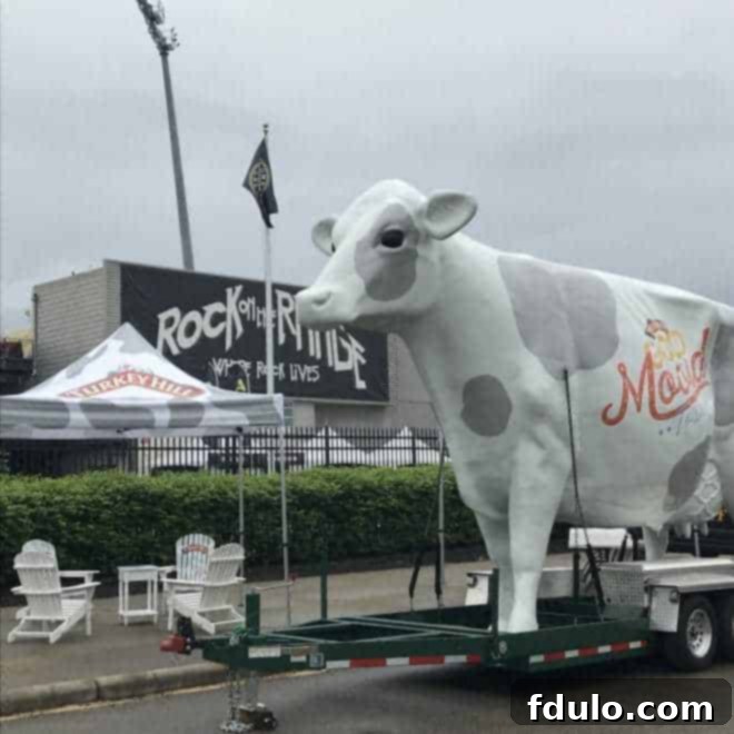 A large inflatable cow mascot representing Turkey Hill's Good Mooed Sampling Tour, standing outdoors at an event, with people in the background.