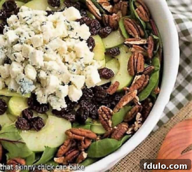Overhead view of a vibrant Winter Salad featuring crisp apples, toasted pecans, crumbled blue cheese, and ruby-red dried cherries. The salad is beautifully arranged, showcasing its fresh, colorful ingredients.