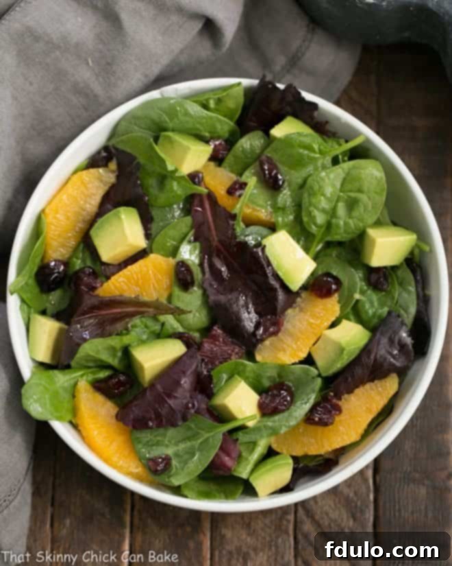 Sunny Citrus Avocado Spinach Salad 2 A vibrant Citrus Spinach Salad with Avocados and Oranges, drizzled with a zesty lemon Dijon vinaigrette, served in a white bowl.