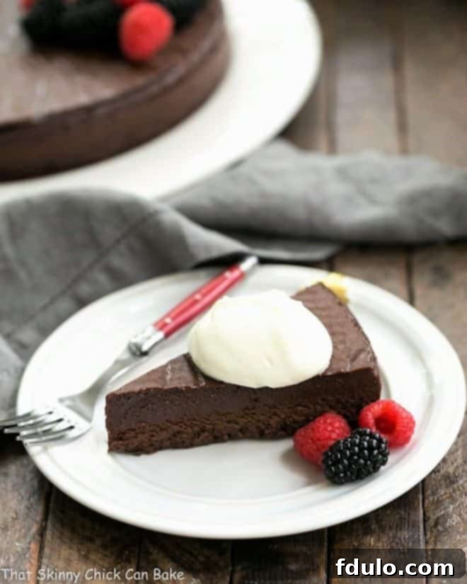 Homemade Chocolate Cake Recipe from Princeville Hotel - 5 simple ingredients make for one decadent, outrageously delicious dessert! Slice of Flourless Cake Chocolate topped with whipped cream on a round white dessert plate with a red handled fork