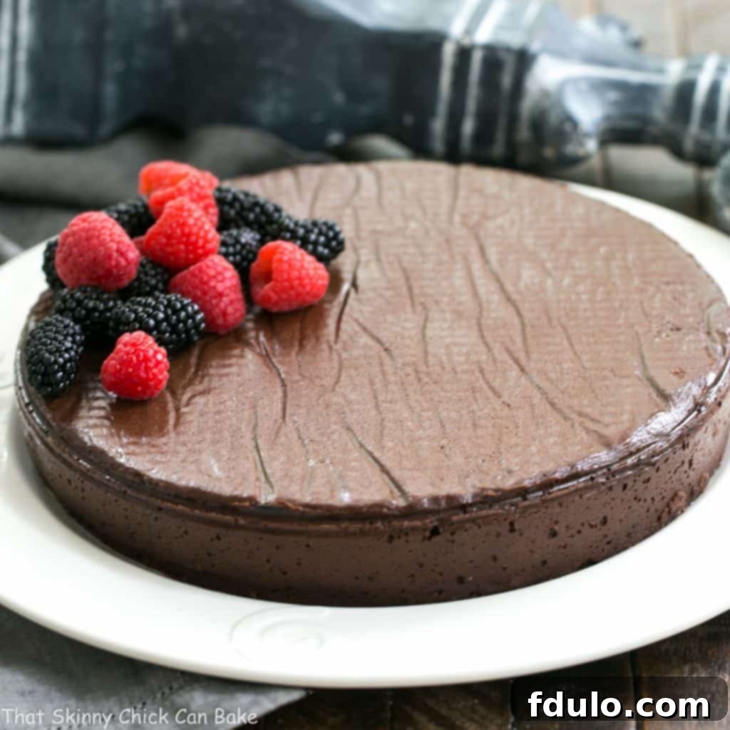 Flourless Cake Chocolate from Princeville Hotel - 5 simple ingredients make for one decadent, outrageously delicious dessert! Flourless Cake Chocolate from Princeville Hotel on a white serving plate garnished with fresh berries.