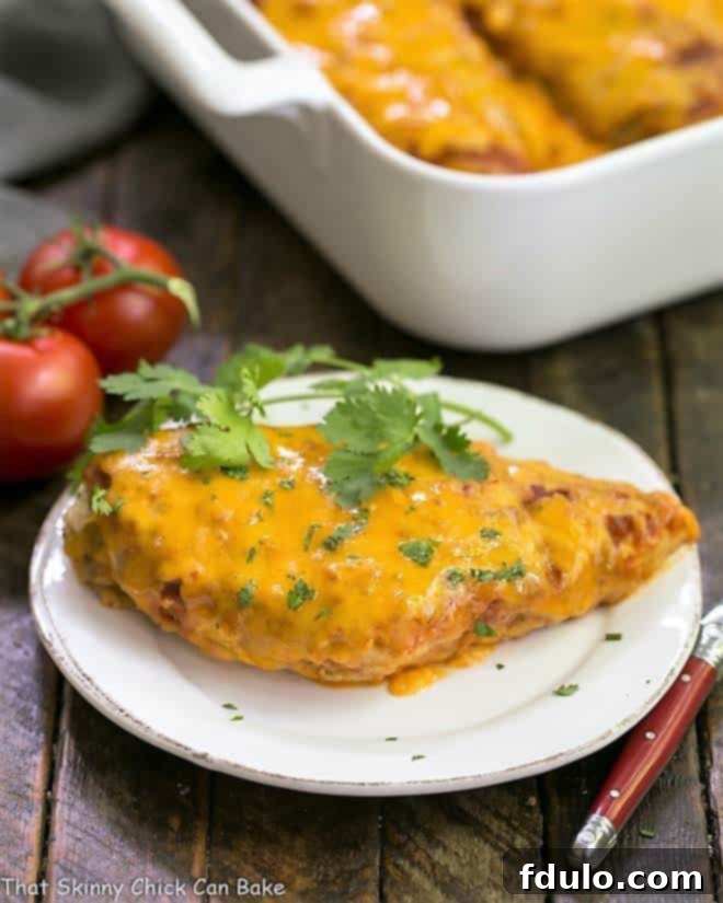 Easy Salsa Chicken on a small white plate with a casserole dish filled with more salsa chicken in the background, showcasing its cheesy topping.