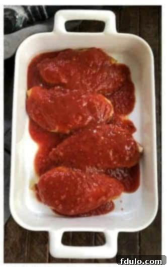 Step 2: Salsa being poured generously over the browned chicken breasts in a baking dish.