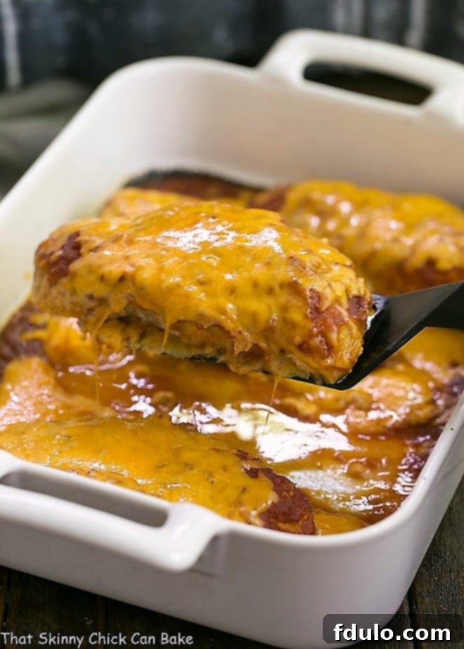 One serving of easy salsa chicken being lifted from a white casserole dish with a black spatula, showing its cheesy topping and tender chicken.