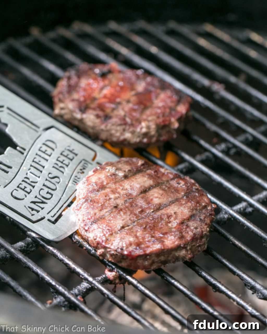 Grilled Guacamole Burger - a grilled beef hamburger topped with melted Monterey jack cheese and a creamy mound of guacamole A Grilled Guacamole Burger sizzling on a charcoal grill, showcasing the melting cheese and the beginning of the perfect sear on the beef patty.