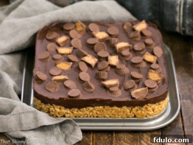 The base layer of Reese's Rice Krispie Treats, made with peanut butter and cereal, pressed into the bottom of a square springform pan, before the chocolate topping is added.