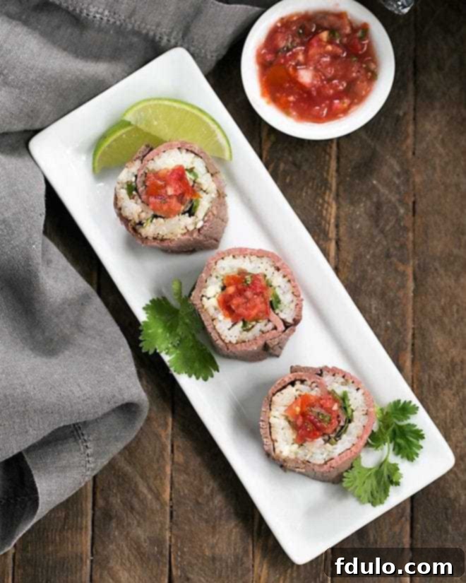 Beefshi - Beef Texan Rolls are a fun twist on classic sushi made with deli beef, sushi rice along with some Tex-Mex flavor boosters! Beefshi - Beef Texan Rolls on a white rectangular tray topped with vibrant salsa