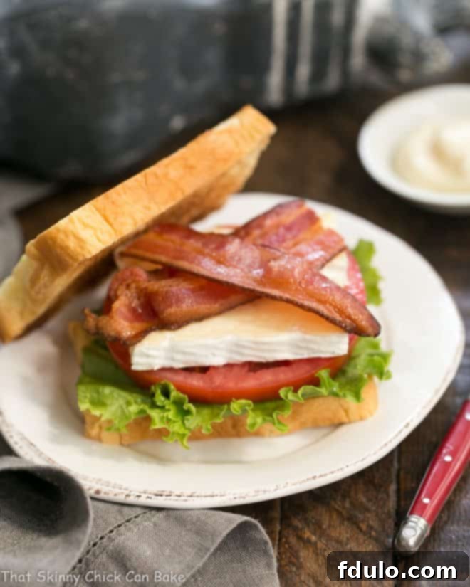 A delicious Brie Bacon Lettuce and Tomato Sandwich on a white plate, showcasing the creamy Brie.
