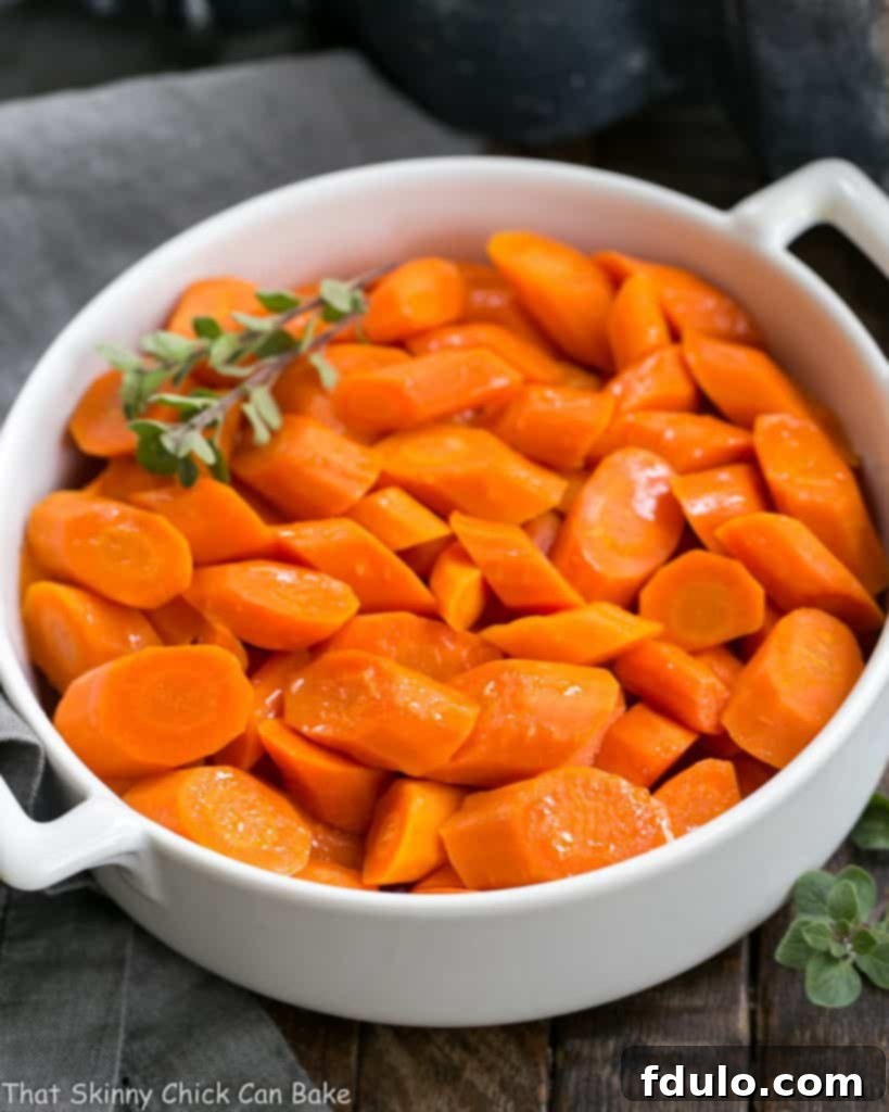 Bourbon Maple Glazed Carrots - An easy way to transform carrots into a restaurant worthy side dish! Bourbon Maple Glazed Carrots in a pristine white ceramic dish, ready to be served as an elegant side dish.