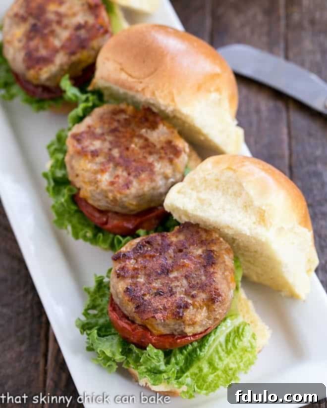 Flavorful Turkey Sliders with Roasted Tomatoes - the ultimate mini burgers for game day! A vibrant line of Turkey Sliders with Roasted Tomatoes displayed on a pristine white serving tray, ready to be enjoyed.