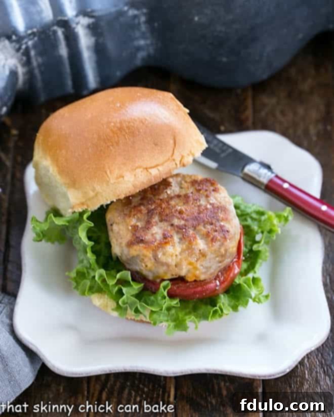 A delicious Turkey Slider with Roasted Tomatoes. A single, perfectly assembled Turkey Slider with Roasted Tomatoes resting on a simple square white plate, highlighting its delicious layers.