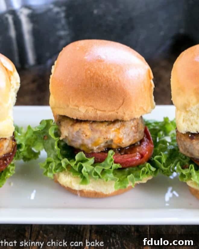 A perfect line of Turkey Sliders with Roasted Tomatoes. An appetizing line of Turkey Sliders displayed on a pristine white serving tray, garnished with fresh herbs, ready for serving.