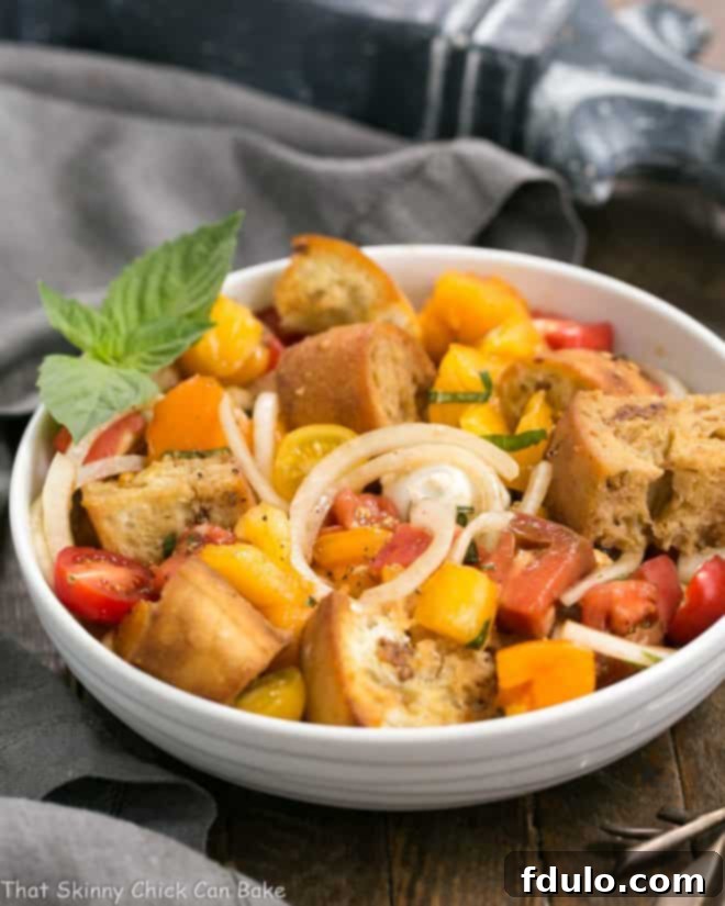 A Summer Tomato and Burrata Panzanella Salad presented in an elegant white ceramic bowl, ready to be served.