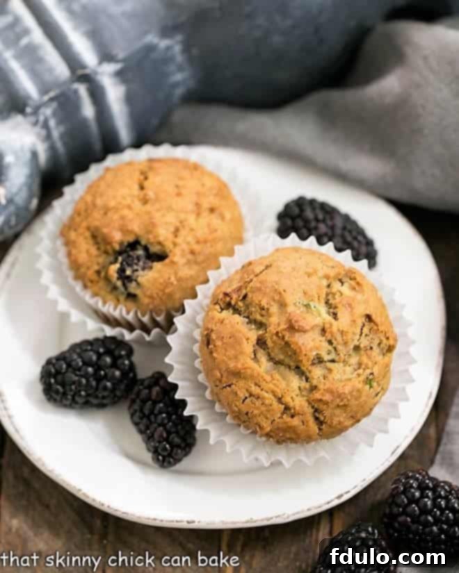 Blackberry Bran Muffins with grated zucchini and full of juicy, plump berries Delicious Blackberry Bran Muffins on a white plate garnished with fresh berries
