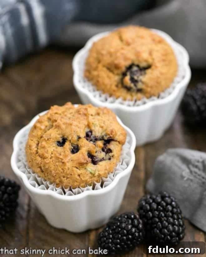 Blackberry Bran Muffins with grated zucchini and full of juicy, plump berries Freshly baked Blackberry Bran Muffins cooling in white ceramic ramekins