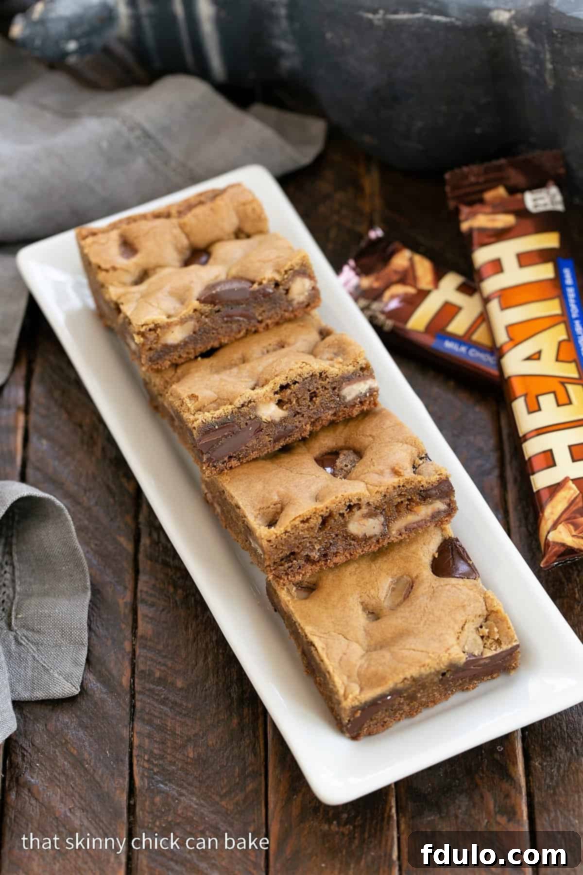 Irresistible Toffee Blondies arranged beautifully on a pristine white tray, accompanied by whole Heath bars, showcasing their golden-brown perfection and tempting texture.