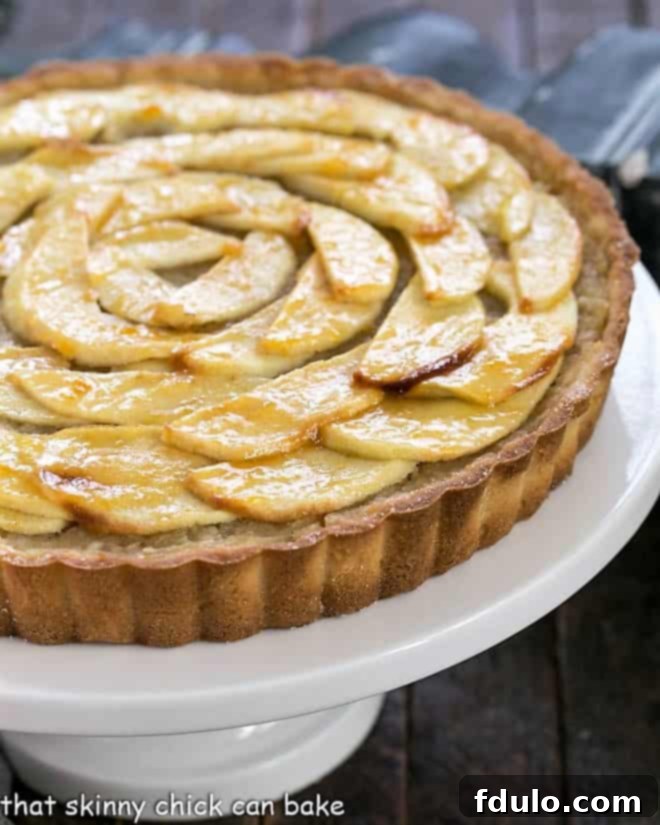 Beautiful French Apple Tart displayed on a white cake stand, ready to serve