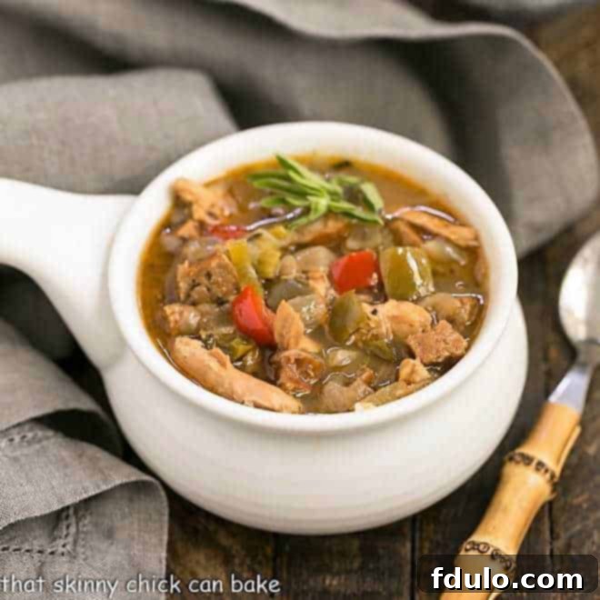 Sausage and Chicken Gumbo in a ceramic soup bowl, garnished with herbs.