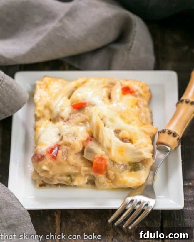 King Ranch Casserole from Scratch on a white plate with a bamboo handled fork, highlighting its creamy texture.