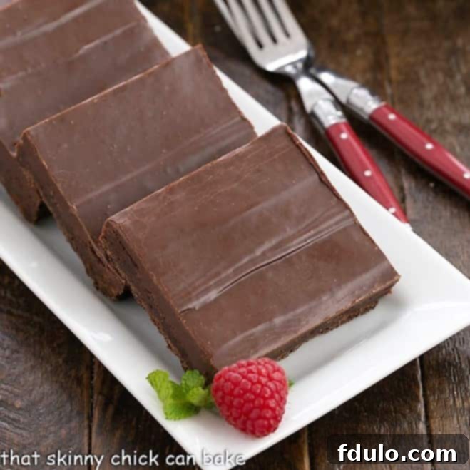 Close-up view of three perfectly fudgy brownie squares on a white ceramic tray, showcasing their rich texture and delicious frosting.