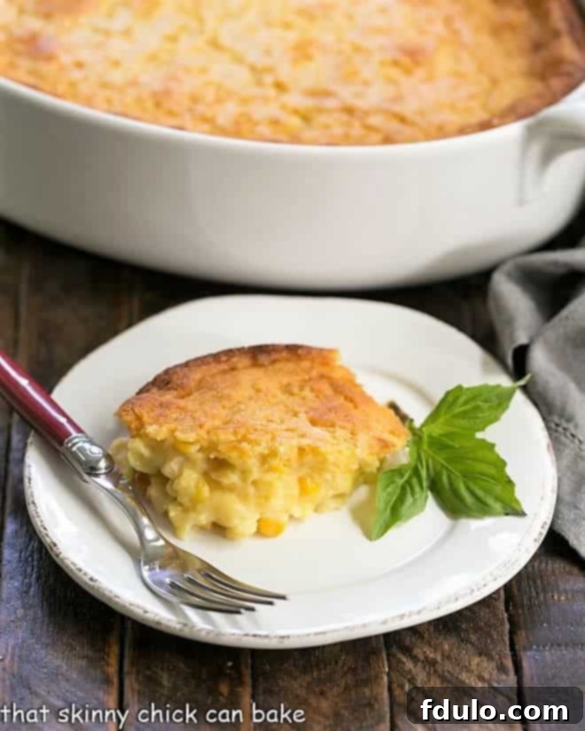 A small white plate holding a serving of Easy Sweet Corn Casserole, garnished with fresh basil leaves.