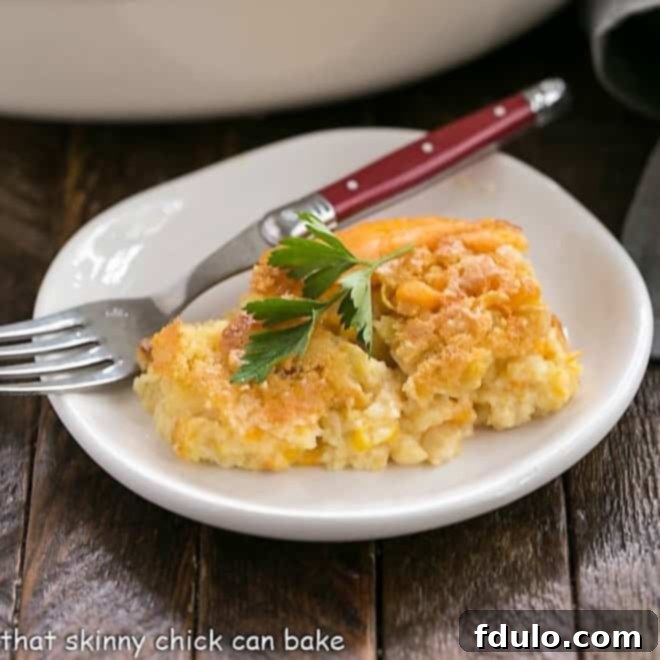 A scoop of Jiffy Corn Casserole on a small white plate with a red-handled fork, showing its delicious texture.