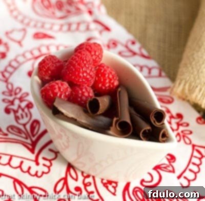 Close-up shot of various dessert garnishes including fresh raspberries, mint leaves, and homemade chocolate curls, ready to adorn the Chocolate Delight.