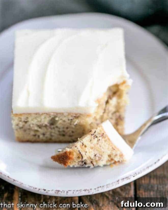 A fork lifts a generous bite of Sour Cream Banana Cake, revealing the soft, moist interior and creamy frosting.
