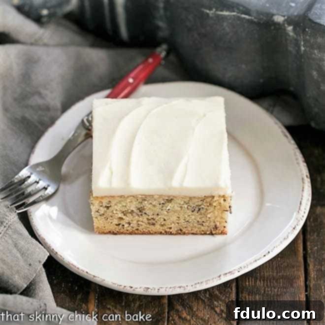 Sour Cream Banana Cake on a round white plate with a red handled fork, inviting a taste.