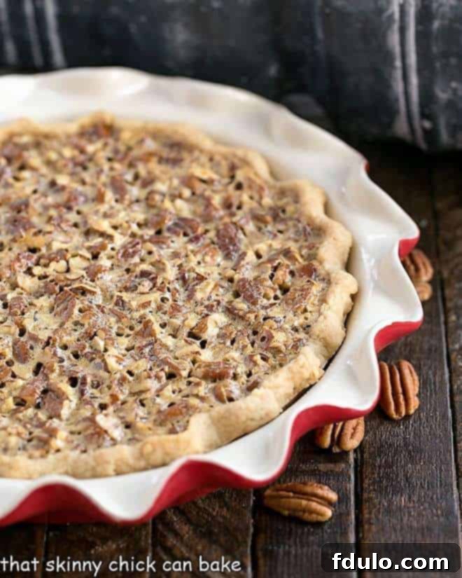 Classic Pecan Pie in a red pie plate with pecan halves.