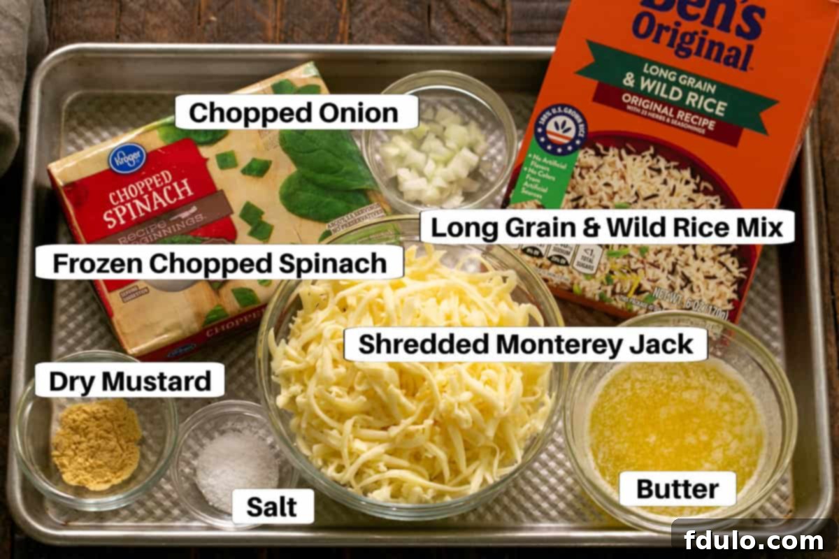 A collection of ingredients for Cheesy Spinach Rice Casserole arranged on a sheet pan, including a box of rice, butter, onions, spinach, and cheese, each clearly labeled.