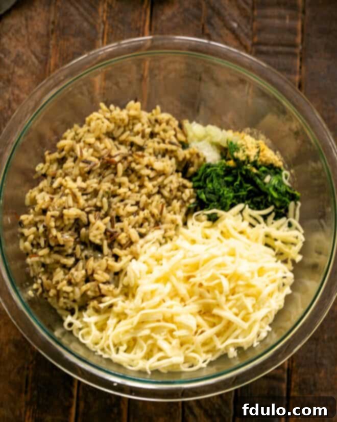 A mixing bowl with cooked rice and shredded Monterey Jack cheese being added to the spinach and onion mixture.