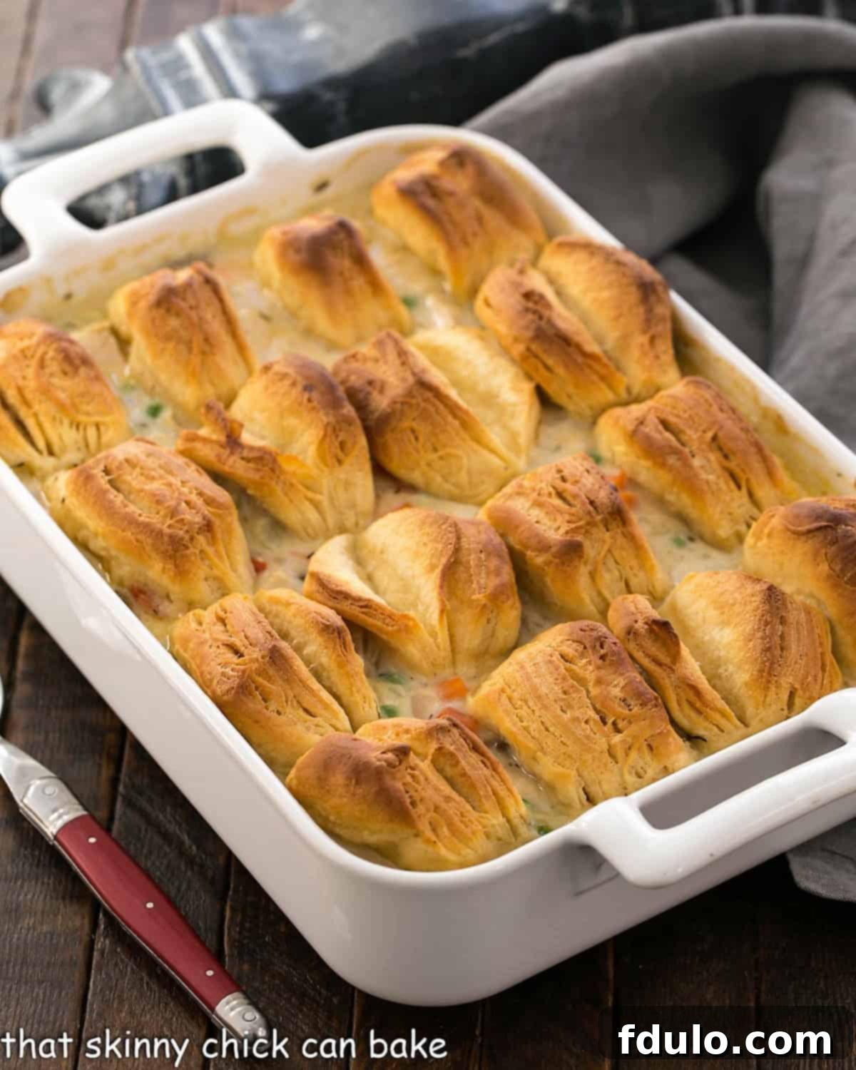 Chicken Pot Pie Casserole - comfort food at its finest topped with the flakiest, tender buttermilk biscuits Chicken Pot Pie in a whiite casserole dish topped with butterflake biscuits.
