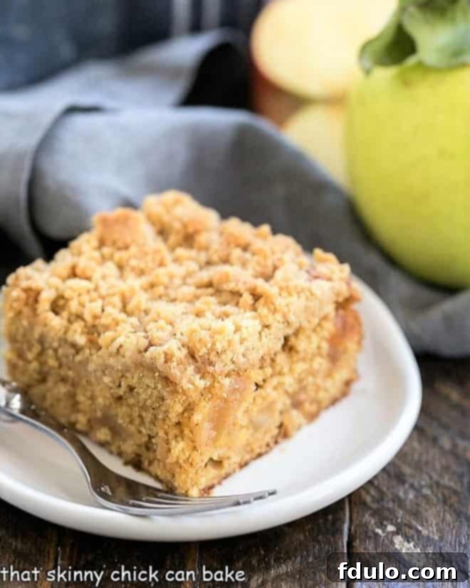 A slice of Apple Streusel Coffee Cake on a small white plate, showing the tender cake, apple filling, and streusel topping.