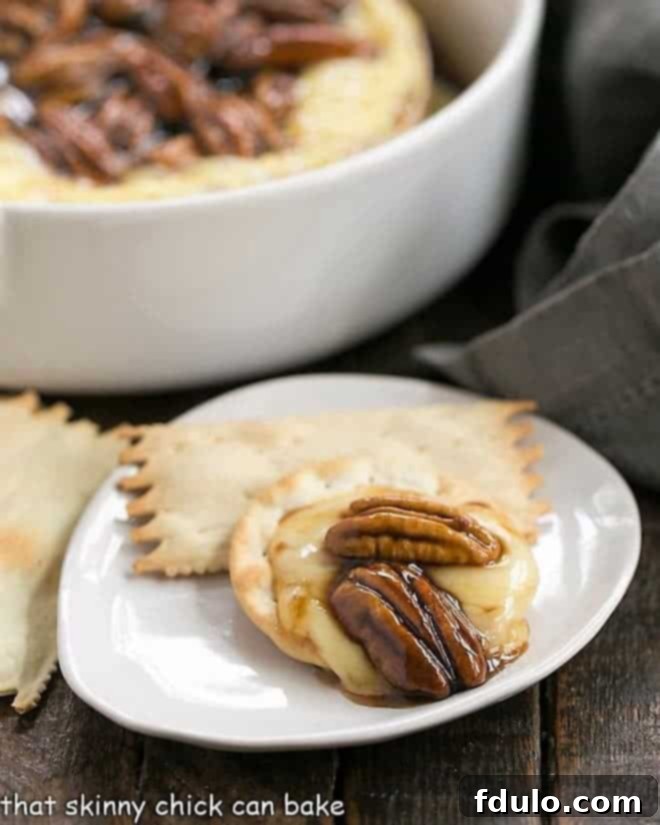 Kahlua Caramel Brie Indulgence 3 Kahlua Caramel Baked Brie on a cracker on a small white plate, ready to be enjoyed.