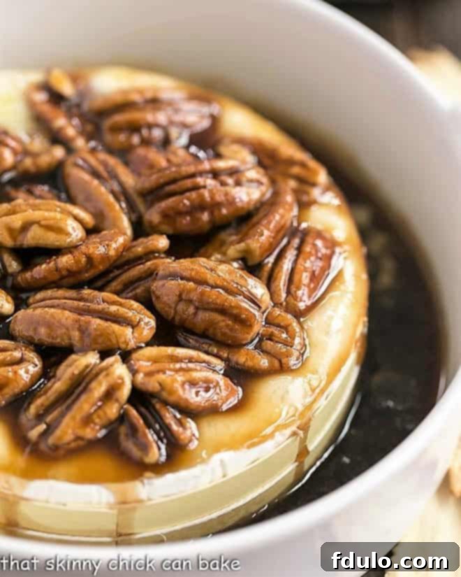 Kahlua Caramel Brie Indulgence 4 Kahlua Caramel Baked Brie in a round ceramic baking dish topped with pecans, ready for serving.