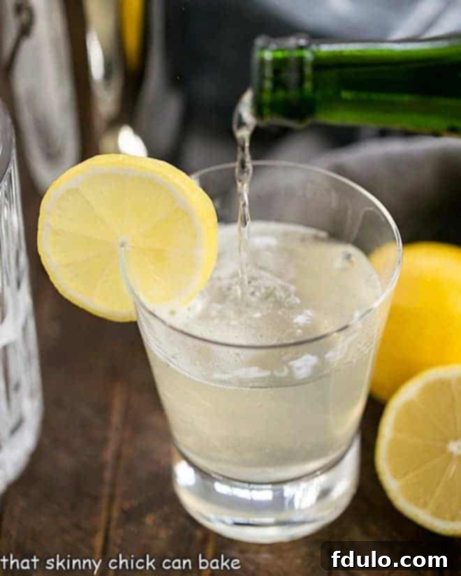 A beautifully garnished French 75 Champagne Cocktail with a fresh lemon slice, perfect for any celebration.