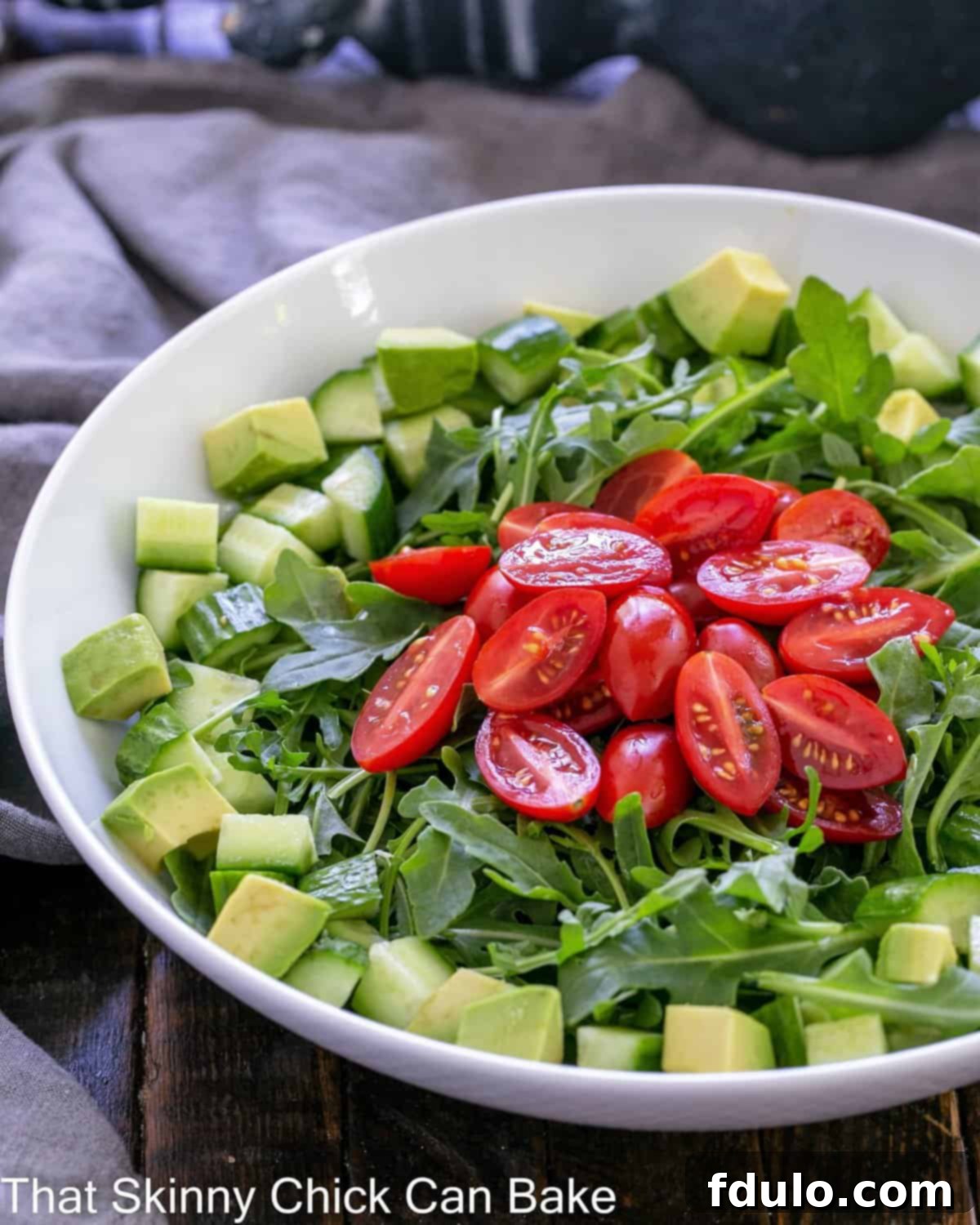 Fresh Rocket salad in a pristine white serving bowl, showcasing vibrant green leaves and colorful vegetables.