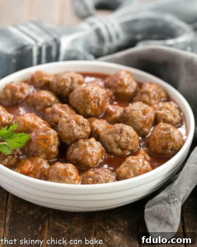 Close-up of apricot glazed cocktail meatballs in a white ceramic bowl, garnished with a sprig of fresh parsley, ready to serve.