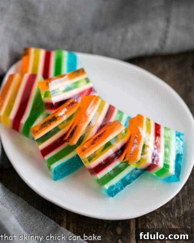 Slices of Layered Jello Rainbow Salad on a white oval dish, showing distinct layers.