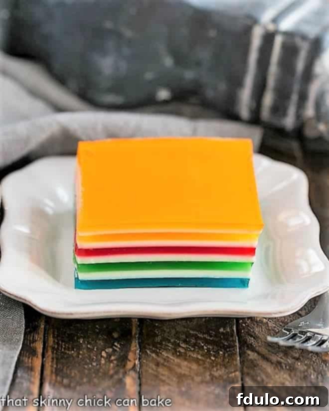 A square of Jello Rainbow Ribbon Salad on a square white plate, ready to be served.