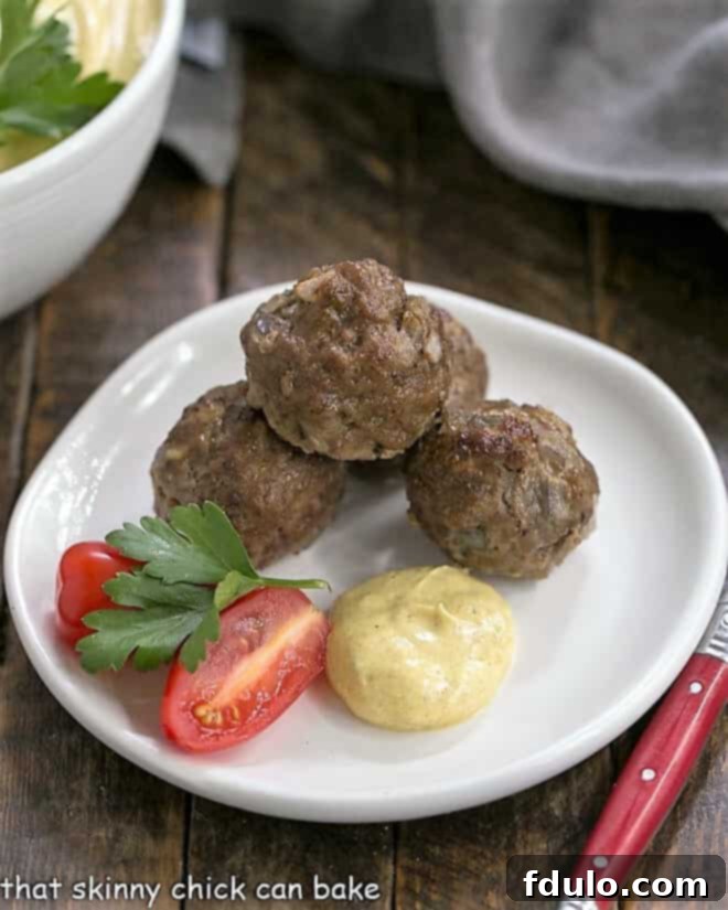 3 Indian meatballs on an appetizer plate with a dollop of yogurt sauce