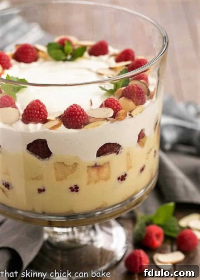 Traditional English Trifle - a classic British dessert with layers of cake, creme anglaise, raspberries, jam and whipped cream Traditional English Trifle side view in a glass trifle bowl, showcasing distinct layers.